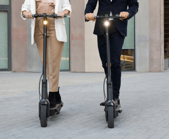 Two adults riding the Segway Ninebot MAX G30 Gen 2 scooter on a city street with stylish attire