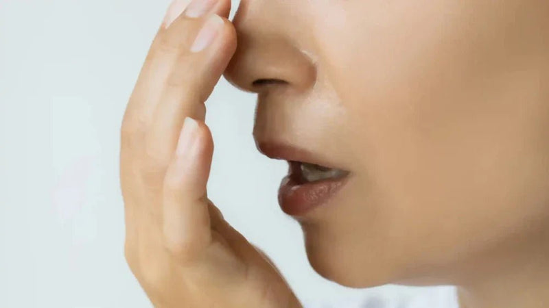 A woman covering her mouth with a concerned expression while speaking because of the bad smell of her mouth.