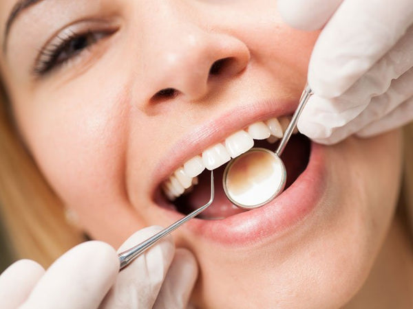 Dentist checking clean teeth with a mirror, showing effective plaque breakdown and routine oral health care.