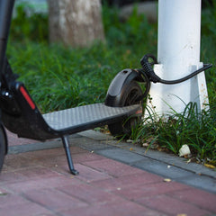Edinco bike and scooter lock securing a scooter to a pole on a sidewalk