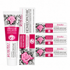 A 3-pack bundle of Rose Rio Homeopathic Toothpaste in Damascena Rose Water, featuring a tube and boxes on a reflective surface. The packaging denotes exact therapeutic claims: aromatherapy, anti-inflammatory, breath-refreshing, and anti-caries prophylaxis. Formulated with natural xylitol and a fresh no-mint aroma. Supplied by UK oral care retailer Edinco.
